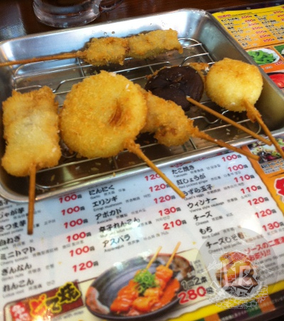 Some breaded and deep fried vegetables, with sticks to pick them up and eat them