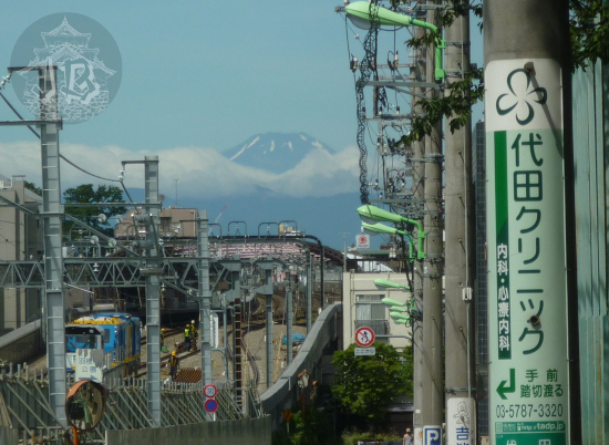 The summit of Mount Fuji peering up through the clouds at the end of a downhill street under construction