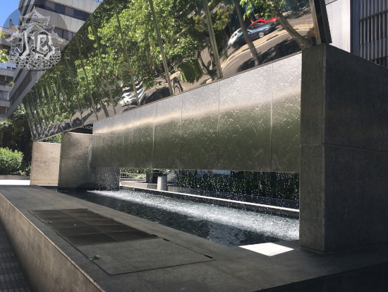 Urban waterfall. The fountain looks like a massive bench, with a thin layer of water dripping from the top