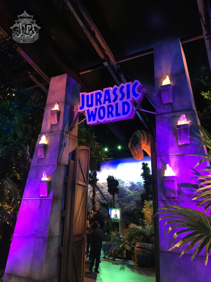 Pretencious gate with two columns on the side, reading Jurassic World. A brontosaurus head peers down at you