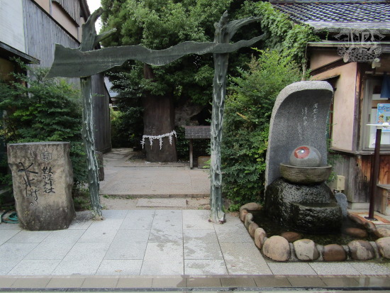 Japanese shrine entrance, depicting the torii as something ghostly. There is a sacred tree just behind the torii.