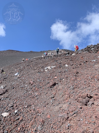 Area closer to the summit of Mount Fuji. There is no vegetation and the ground looks reddish and more like gravel than actual rock.