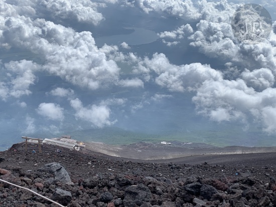 Looking down from the barren area, there are clouds and a river at the foothill