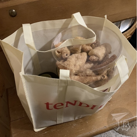 A tote bag reading Tendi (the rest of the writing is obscured), with a box of torreznos inside