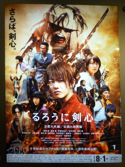 Poster of the movie. It shows a man dressed in red traditional clothes, with an X-shaped scar on his cheek. Behind him, minor characters and the antagonist, covered in bandages.