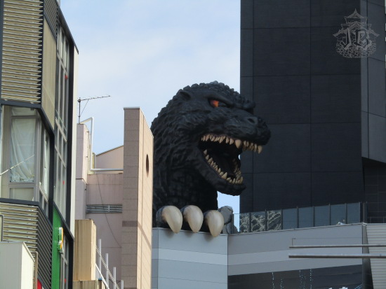Godzilla, a giant mutant iguana, peers throughout the building roofs, roaring