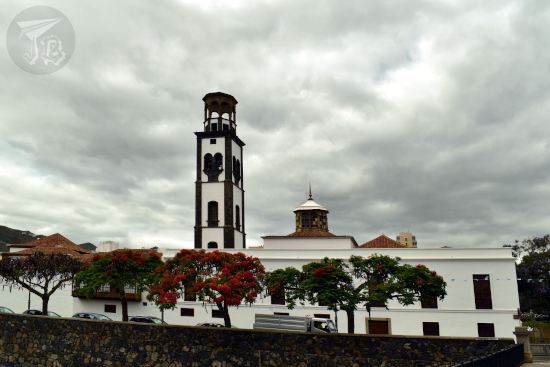 A church with a bell tower. The building is white clay with black rock; this style is typical in the area