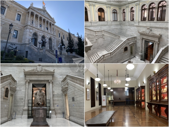Biblioteca Nacional de España. A Neoclassical building in white and grey tones. The exterior has columns and statues of writers. The interior showcases a pair of twin staircases with the statue of one of the most important library directors between both.