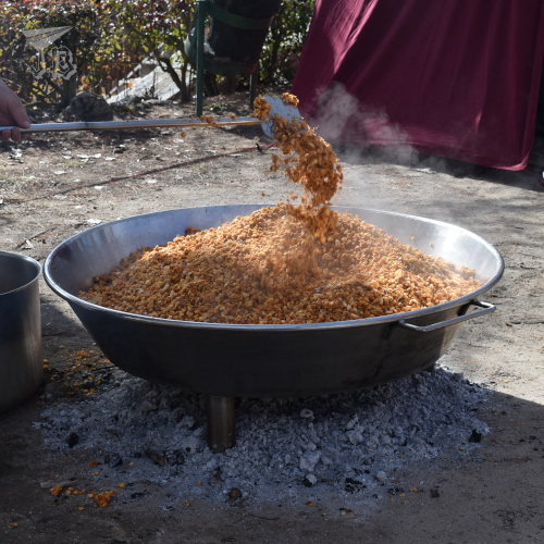 A huge pot with orange breadcrumbs being cooked