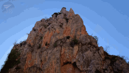 A reddish hill perfectly reflects on a lake.