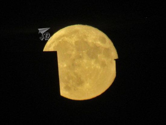 Moon rising behind buildings