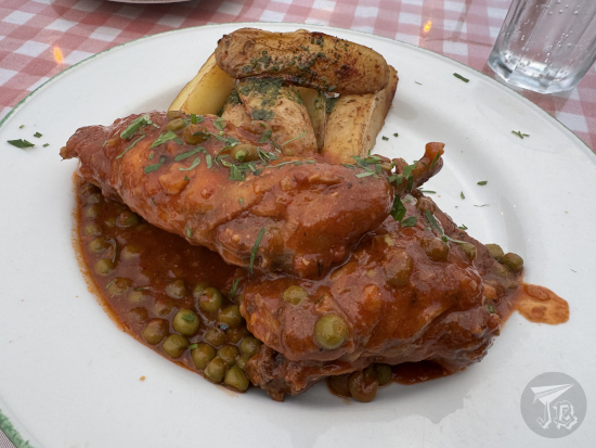 Rabbit cooked in tomato sauce with peas and herbs, and wedged potatoes on the side.