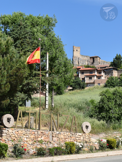 Entrance to the Medieval village of Atienza, with the name of the village, the Spanish flag and a castle in the background.