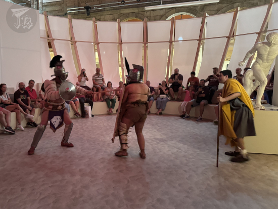 Gladiators fighting. The light-weight's spear has made contact with the heavy-weight's shield.