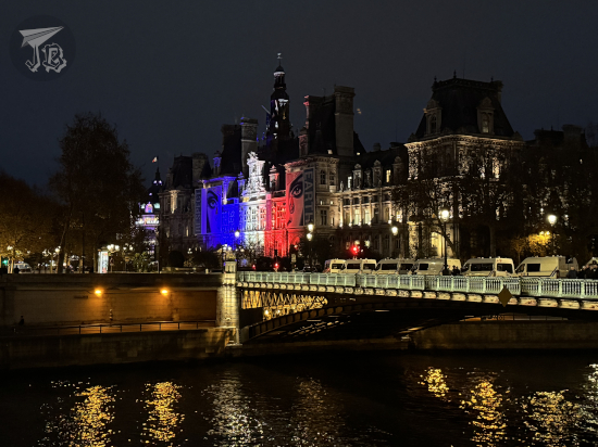 Paris town hall at night with the French flag projected on the façade.