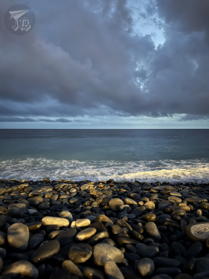 Waves on a pebble beach at sunset.
