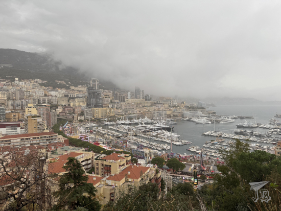 View of Monaco in the middle of a stormcloud, showing the marina and the tall buildings on the coastline.
