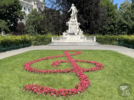 Treble clef made of flowers planted in front of a Mozart statue